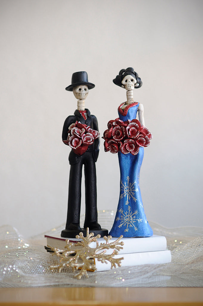 Hand-made clay figurine, Cynthia is wearing a curve-skimming blue dress with silver details on her dress.She is holding a red rose bouquet. Her date, Diego is also holding a red rose bouquet that matches Cynthia's bouquet. All our Catrinas are made in Mexico and shipped worldwide. Add a classy touch of Mexican culture to your home. 