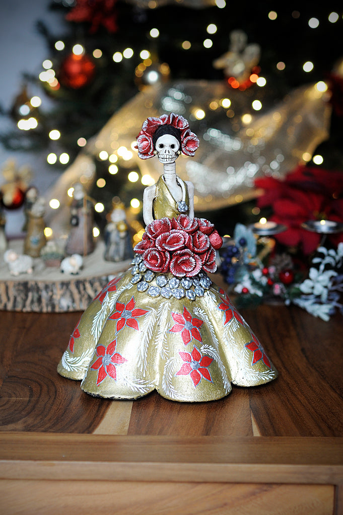 Hand-made clay figurine, Catrina Amanda in Gold is a stunning Catrina created to celebrate Christmas. The artist gave her a gold dress with hand-painted poinsettias. To finish off the look, the artist gave her a red rose bouquet that matches her headpiece. All our Catrinas are made in Mexico and we ship worldwide. Add a classy touch of Mexican art to your home.
