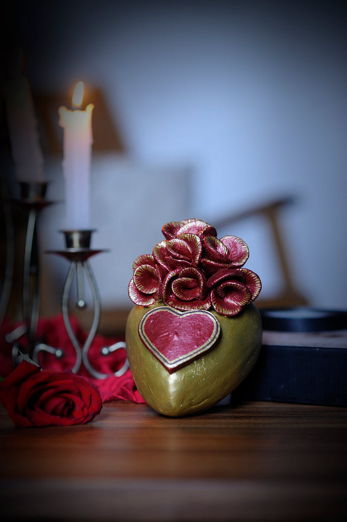 Hand-made clay heart, painted in gold. For decoration, the artist added a heart and a bouquet of red roses with splashes of gold. This beautiful Valentine's Day heart can also be hung on a wall. All our Catrinas and hearts are made in Mexico and we ship worldwide. Add a classy touch of Mexican art to your home.
