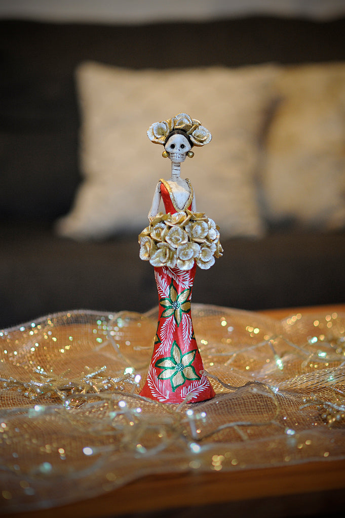 Hand-made clay figurine, Cynthia is wearing a curve-skimming red dress with gold details on her dress as well as hand-painted poinsettias. She is holding a gold rose bouquet. All our Catrinas are made in Mexico and shipped worldwide. Add a classy touch of Mexican culture to your home. 