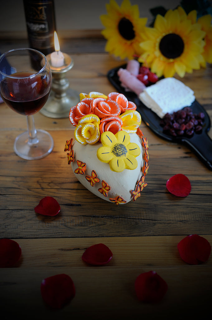 Hand-made clay heart, painted in white, this heart has butterflies and a mix of yellow and orange flowers that match the colors of the butterflies. Give the gift of friendship this Valentine's Day. This beautiful heart can also be hung on a wall to decorate your house. All our products are made in Mexico and we deliver worldwide. Add a classy touch of Mexican art to your home. 