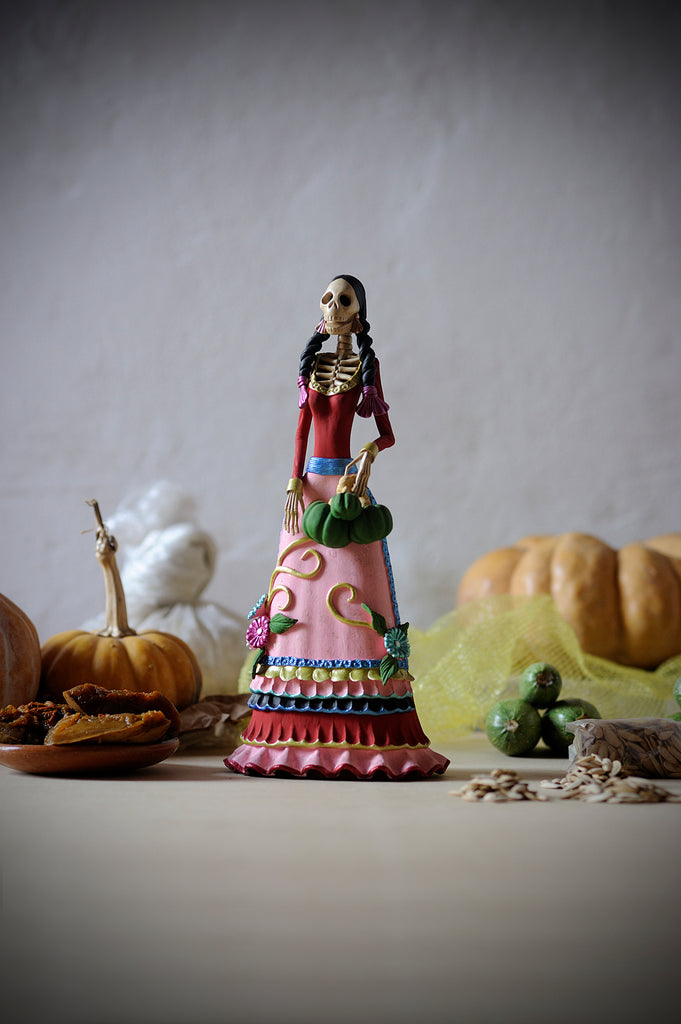 Hand-made clay figurine, Catrina Milagros is part of our El Mercado Collection. She is wearing a beautiful gown with impressive ruffling at the bottom. She is also wearing a pink apron with detailing at the bottom. All our Catrinas are made in Mexico and we ship worldwide. Add a classy touch of Mexican art to your home. 
