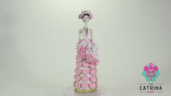 Catrina Isabela is part of our Valentine's Day Catrina collection.  She is wearing a fantastic white dress with pink hand-made hearts. We decided to give her a bouquet of pink and white flowers to match her beautiful headpiece. At the bottom, the dress is lined with gold detailing.  If you are looking for the perfect Valentine's Day gift, consider getting a Catrina, these beauties last forever and will look amazing in any room in your house!