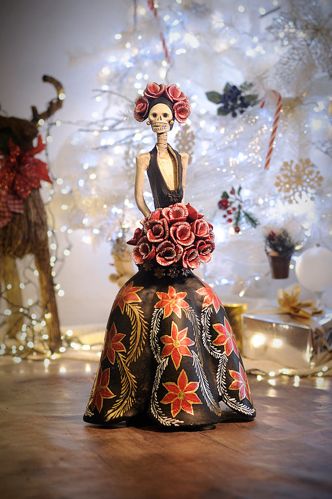 Hand-made clay figurine, Catrina Fernanda is ready for the Christmas party, she is wearing a beautiful black dress, decorated with hand-painted poinsettias and small gold flowers around her bouquet of roses. She is also wearing a beautiful headpiece. Add a classy touch of Mexican art to your home or office. All our Catrinas are made in Mexico and shipped worldwide.