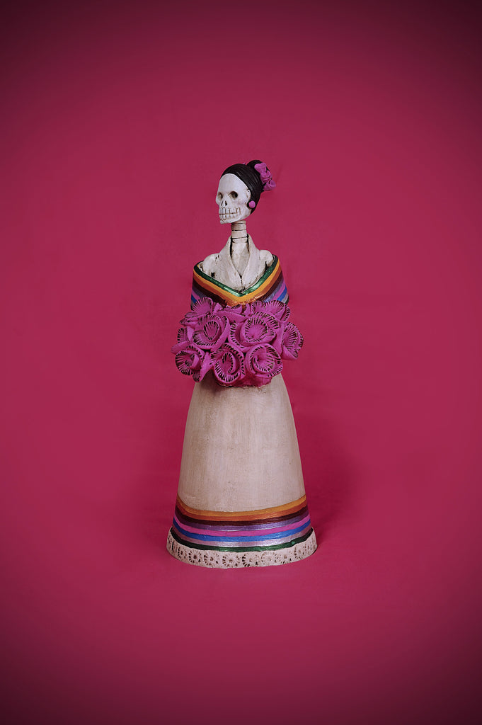 Hand-made clay figurine, the bottom of her dress and the wrap on her shoulders are painted to represent Mexican colors. She is holding a bouquet of pink roses that match the roses she is wearing for a headpiece. Bring a touch if Mexican culture to your home. We ship worldwide.