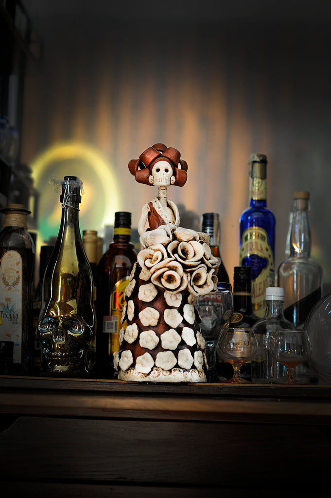 Hand-made clay figurine, the dress and hair are painted in rust and some details on the dress like the flowers on the dress and bouquet are painted in ivory. All our Catrinas are made in Mexico and shipped worldwide. Add a classy touch of Mexican art to your home.