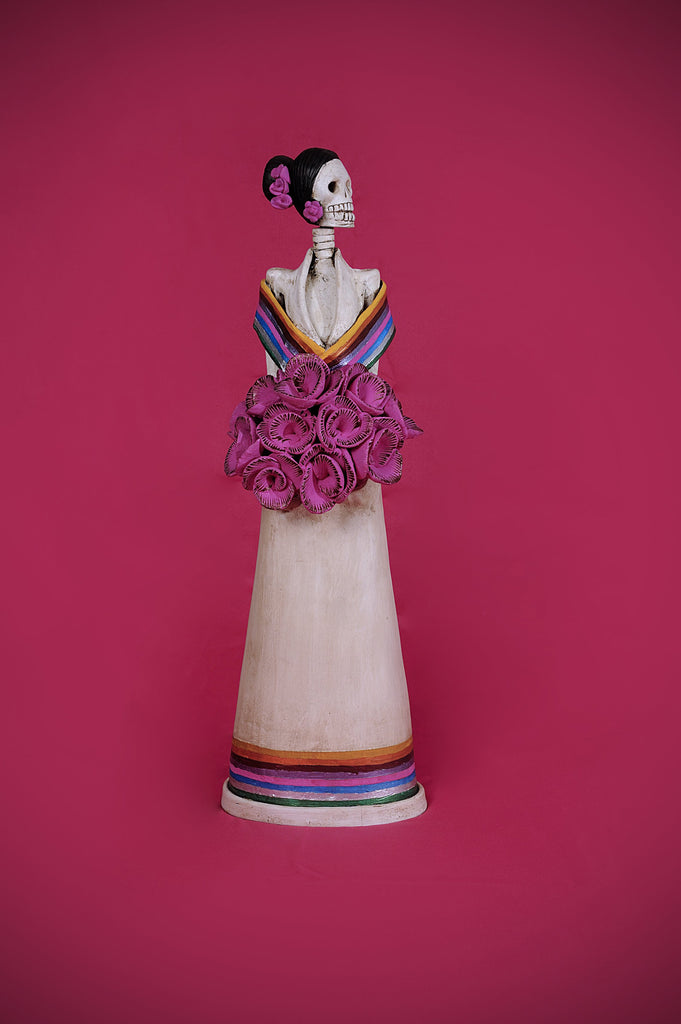 Hand-made clay figurine, the bottom of her dress and the wrap on her shoulders are painted to represent Mexican colors. She is holding a bouquet of pink roses that match the roses she is wearing for a headpiece. Bring a touch if Mexican culture to your home. We ship worldwide.