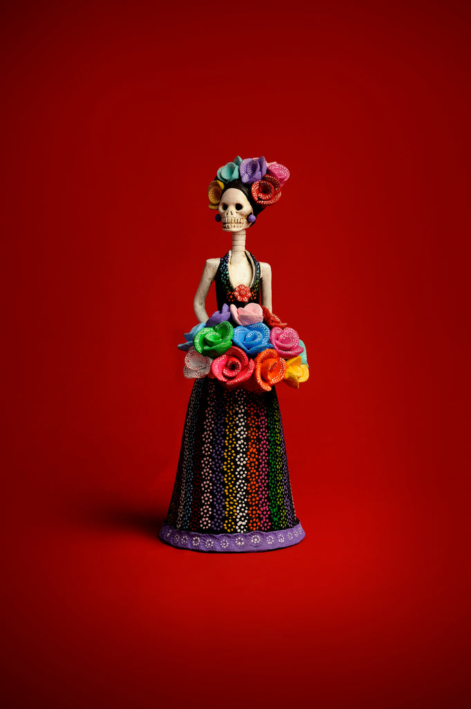 Hand-painted Catrina Alicia in a colorful dotted sleeveless gown, holding a cascading flower bouquet.
