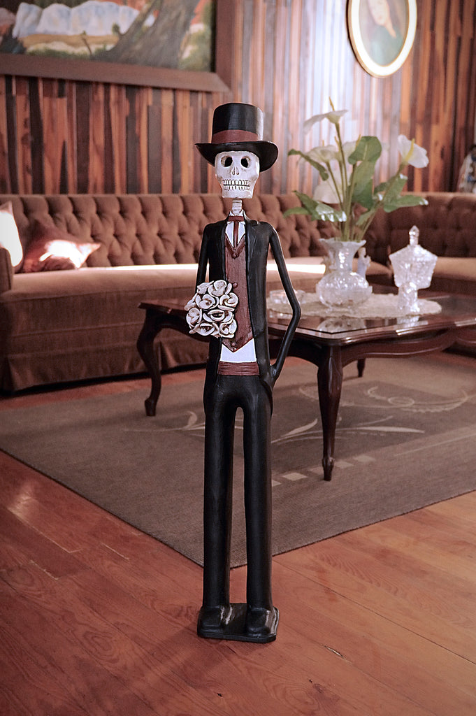 36 inch tall hand-made clay figurine, Catrin David is wearing a black tux with burgundy details. This stunning Catrin looks incredible by himself or next to his female counterpart Angela. All our Catrinas are made in Mexico and we ship worldwide. Add a classy touch of Mexican art to your home.