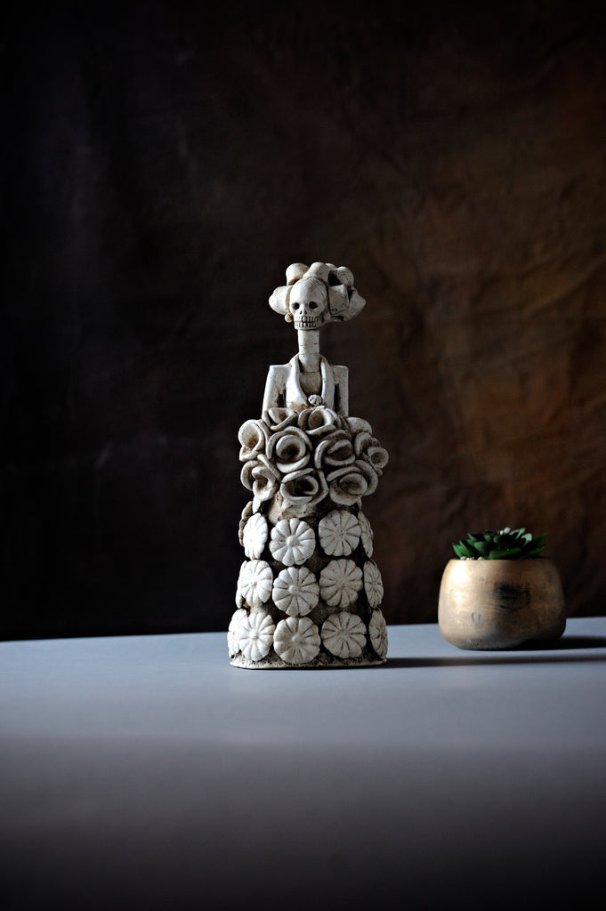 Hand-made clay figurine, Catrina Julia is wearing a cute dress covered in daisies, and to finish off her look, she is holding a rose bouquet. All our Catrinas are made in Mexico and we ship worldwide. Add a classy touch of Mexican culture to your home.