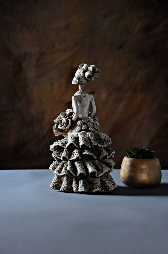 Hand-made clay figurine, painted in ivory with stunning details on her ruffled dress. All our Catrinas are made in Mexico, we ship worldwide. Add a classy touch of Mexican art to your home.