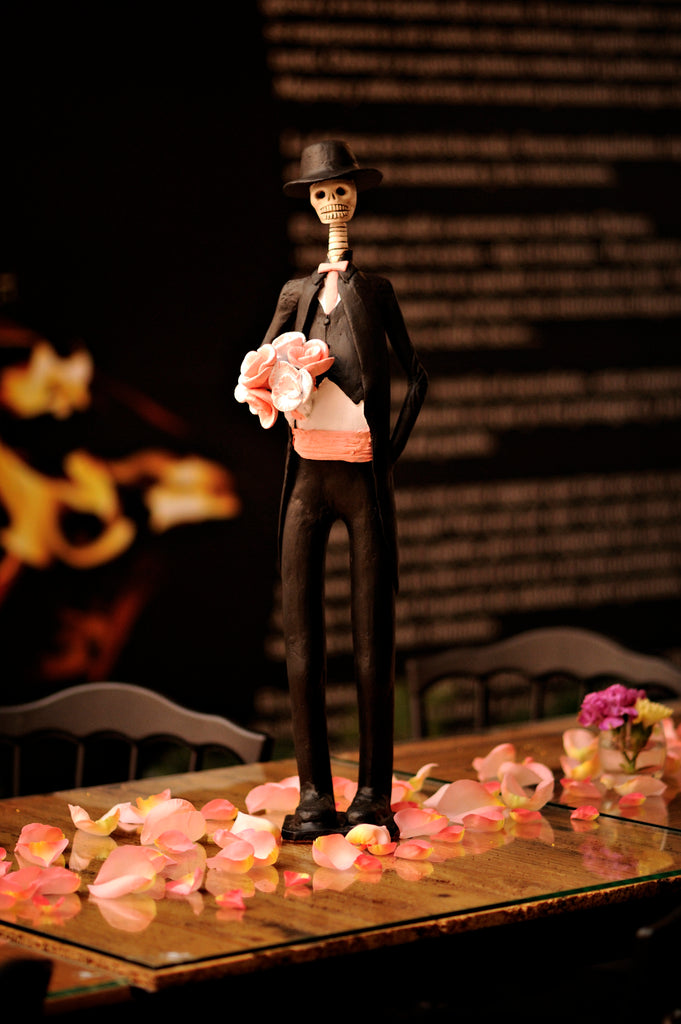 26 inch tall, hand-made clay figurine. Our male Catrin Brandon is wearing a traditional tux, with a pink waistcoat and pink bow tie that match the pink flower bouquet he is holding for his lovely bride. He is also wearing a hat to compliment his look. All our Catrinas are made in Mexico. We ship worldwide. Add a classy touch of Mexican art to your home or office! 