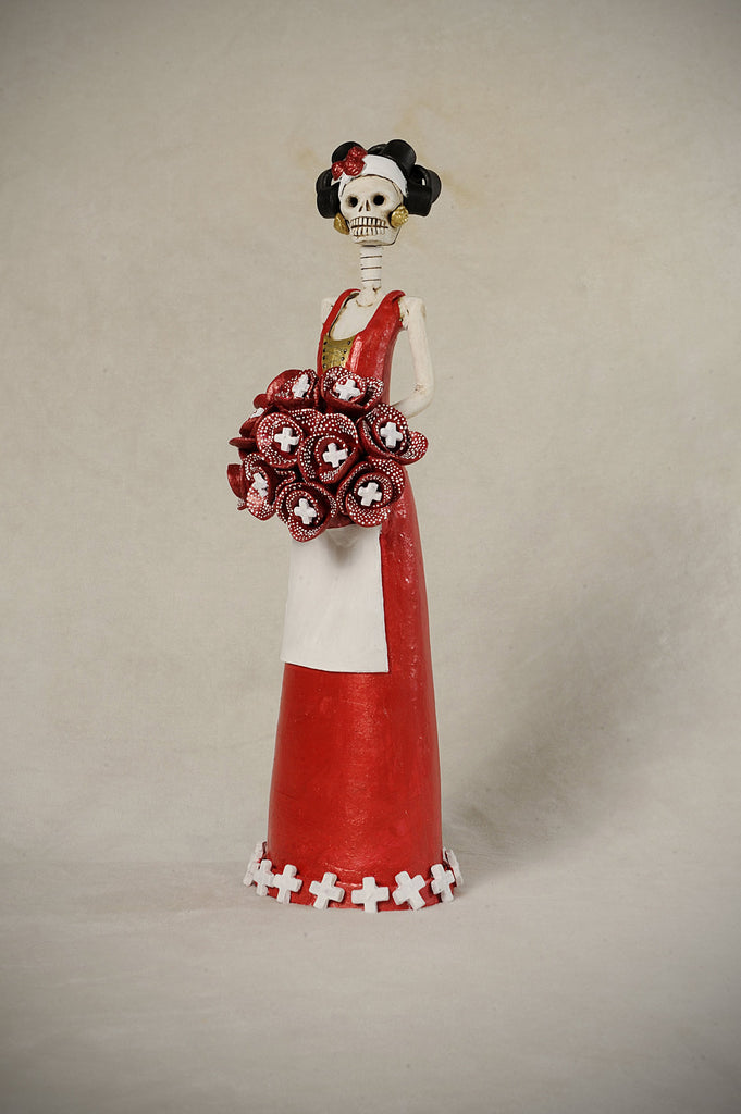 Hand-made clay figurine, Catrina Miss Switzerland is wearing a red dress with a white apron and cute detailing at the bottom of the dress to represent Switzerland. All our Catrinas are made in Mexico and we ship worldwide. Add a classy touch of Mexican culture to your home.  