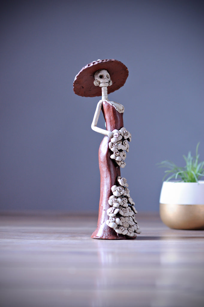 Catrina Catalina belongs to the small Catrina’s collection, but what’s wrong with being small when she is one of a kind!  Our artist has created Catalina, a unique piece of art by displaying a sexy mermaid dress, a creative design with pretty Forget me Not’s on the skirt and bouquet. She is dressed in the original Catrina Hat as Diego Rivera painted it. 