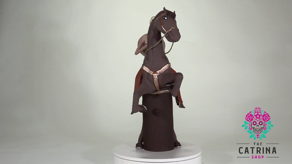 Catrin Julian is a handsome charro wearing a light brown suit with incredible gold detailing. Julian is riding on his noble steed Rayo, which is a beautifully made horse painted in brown with gold detailing as well. This stunning piece of art will look amazing in your home! Add a classy touch of Mexican art to your home.