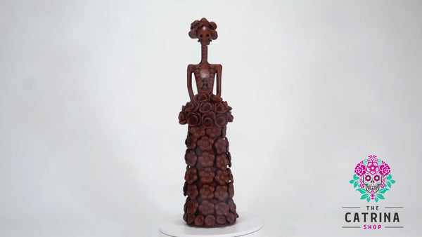 Hand-made clay figurine, Catrina Natalia is a beautiful Catrina wearing a long A-line shaped dress with flowers all around her dress. She is also holding a rose bouquet. Add a touch of Mexican art to your home. All our Catrinas are made in Mexico and ship worldwide.  